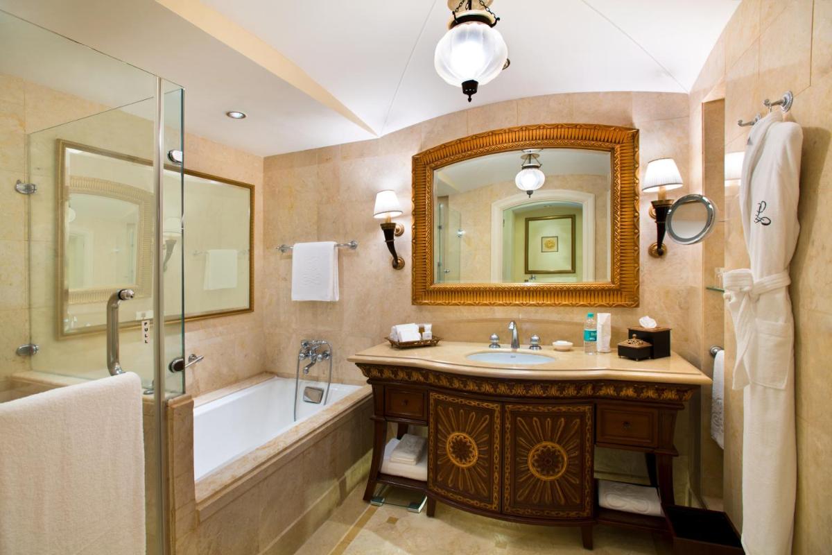 a bathroom with a tub and a sink and a mirror at The Leela Palace Bengaluru in Bengaluru a bathroom with a tub and a sink and a mirror at The Leela Palace Bengaluru in Bengaluru