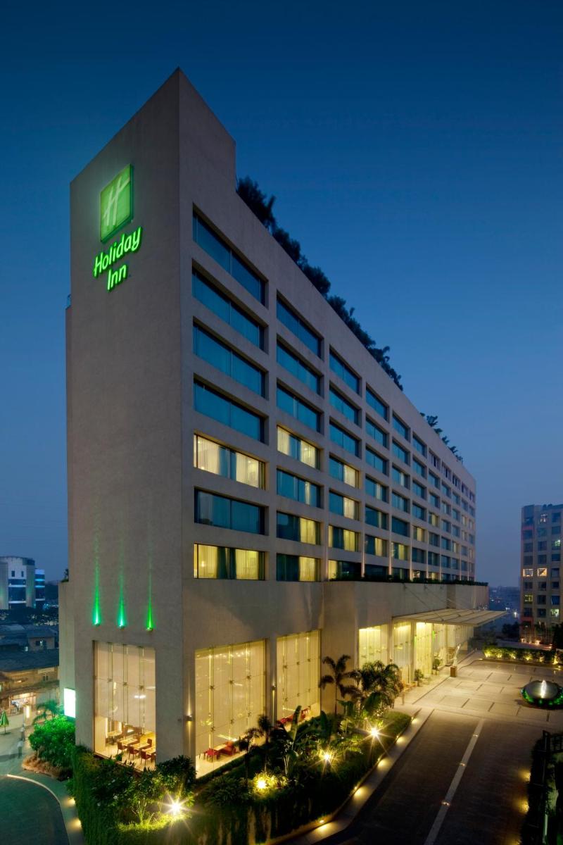 a hotel building with a sign on it at night at Holiday Inn Mumbai International Airport by IHG in Mumbai a hotel building with a sign on it at night at Holiday Inn Mumbai International Airport by IHG in Mumbai