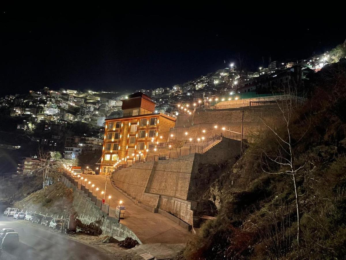 a building with lights on a hill at night at The Orchid Shimla in Shimla