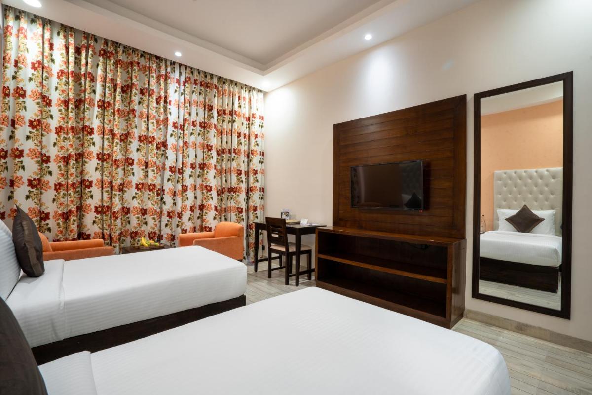 a hotel room with two beds and a television at The Orchid Shimla in Shimla
