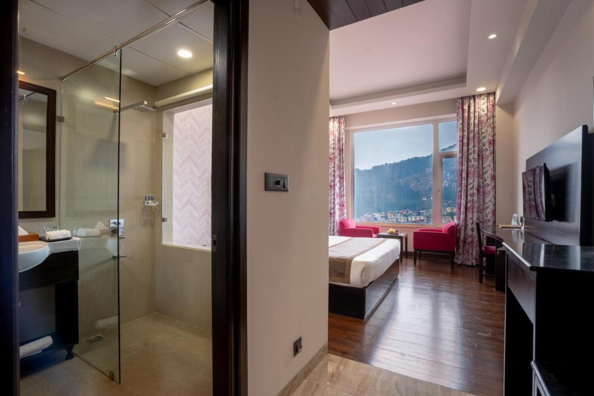 a hotel room with a bed and a glass shower at The Orchid Shimla in Shimla