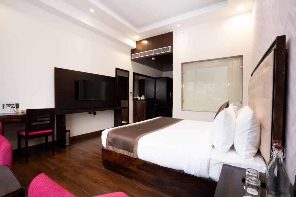 a hotel room with a large bed and a desk at The Orchid Shimla in Shimla