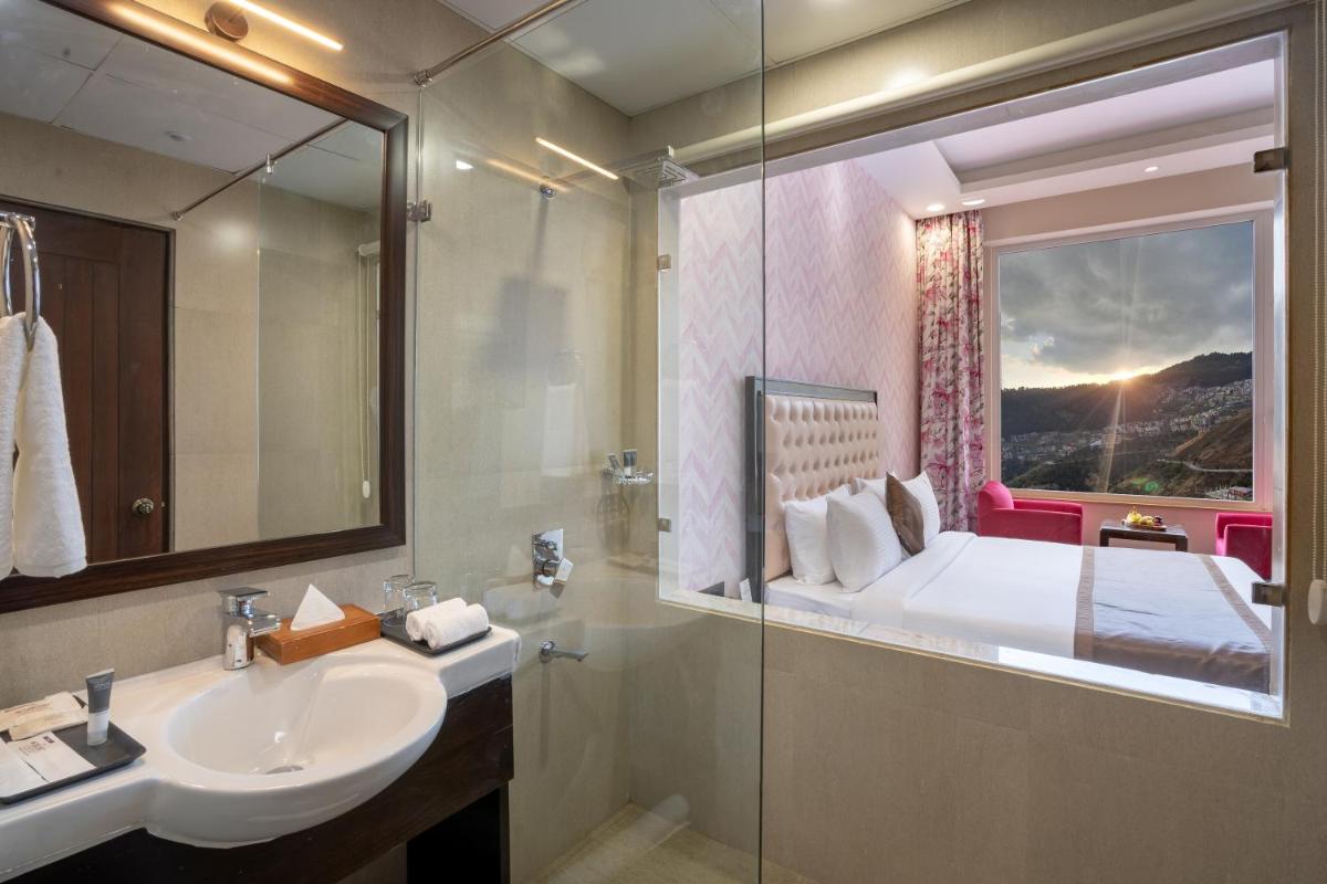 a bathroom with a sink and a bed with a window at The Orchid Shimla in Shimla