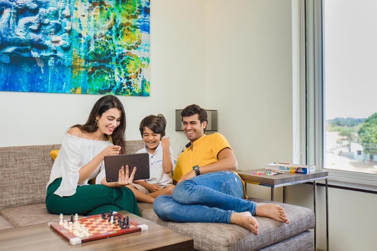 a group of three people sitting on a couch playing chess at The Residency Towers, Rameswaram in Rāmeswaram