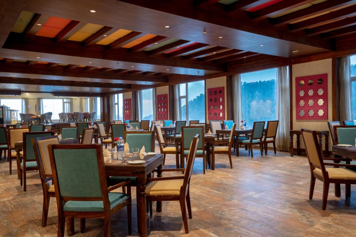 a dining room with tables and chairs and windows at The Orchid Shimla in Shimla