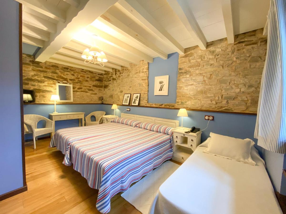 Un dormitorio con dos camas y una pared de piedra. en Hotel Casa Cachón, en Tol 50 fotos más