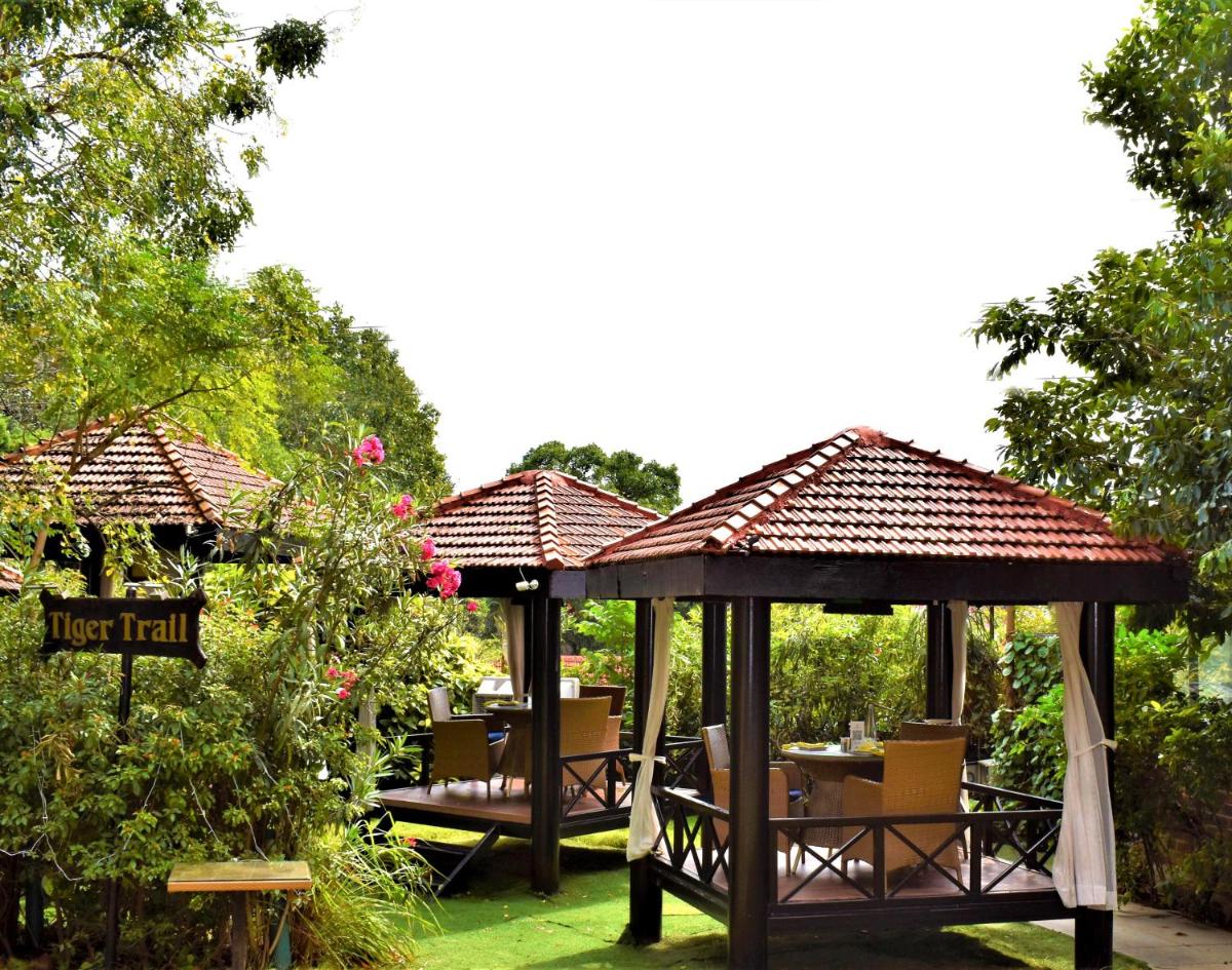 two gazebos with tables and chairs in a garden at Hotel Royal Orchid Bangalore in Bengaluru