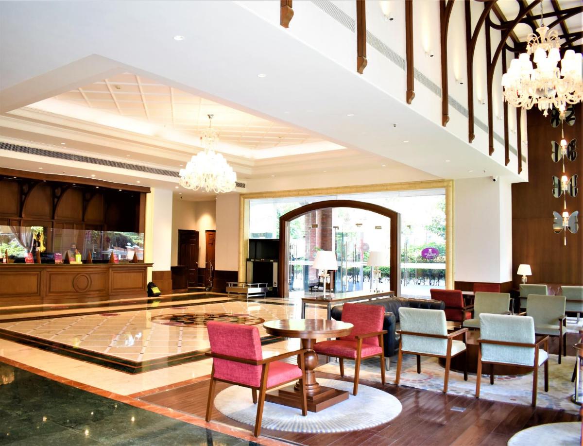 a lobby with chairs and a table in a building at Hotel Royal Orchid Bangalore in Bengaluru