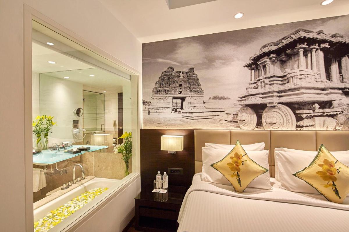 a bedroom with a bath tub and a large painting on the wall at Hotel Royal Orchid Bangalore in Bengaluru