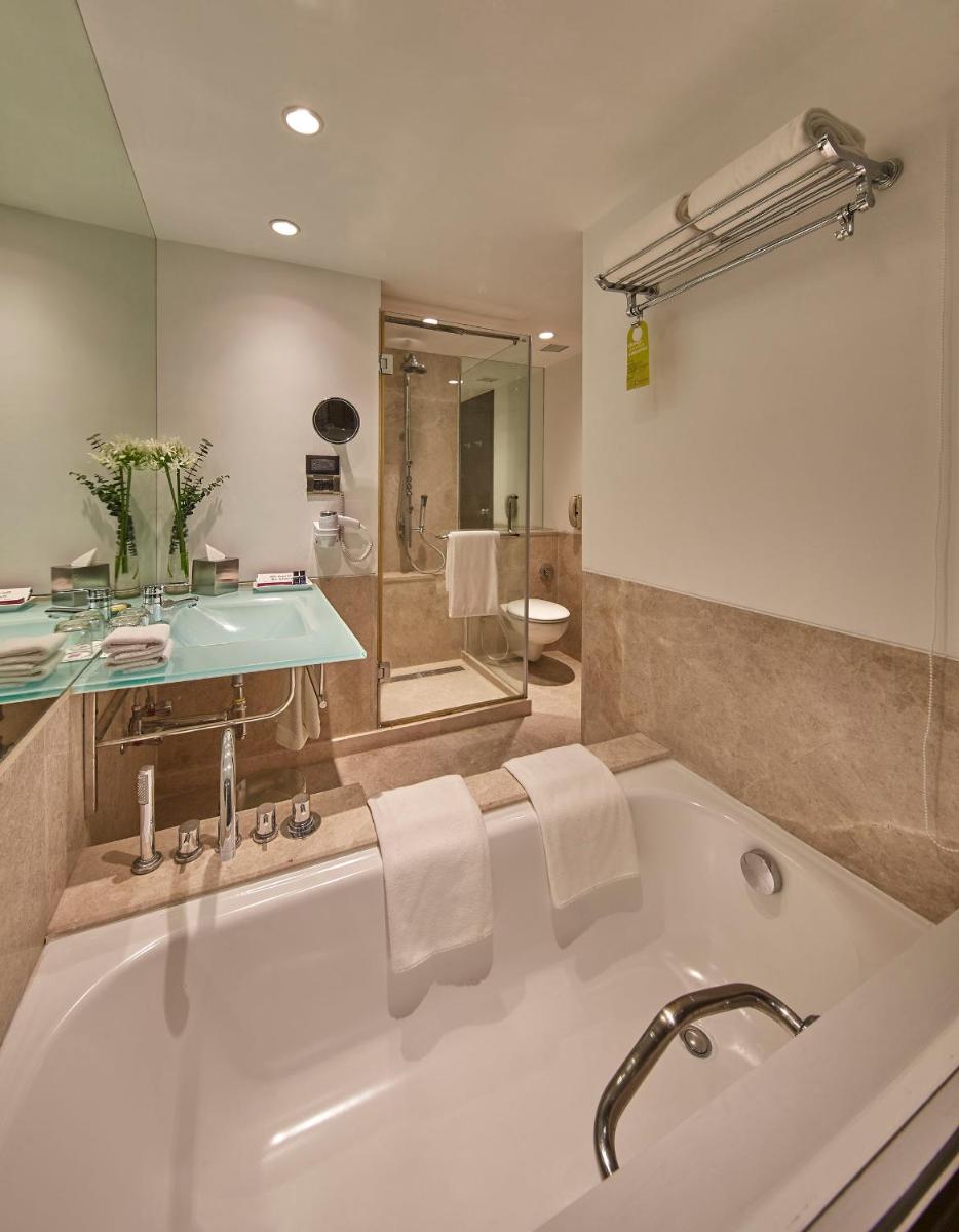 a bathroom with a bath tub and a sink at Hotel Royal Orchid Bangalore in Bengaluru a bathroom with a bath tub and a sink at Hotel Royal Orchid Bangalore in Bengaluru