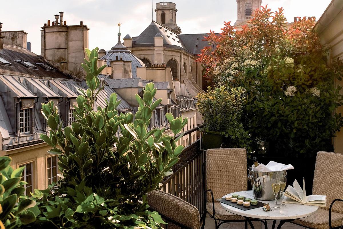 - un balcon avec une table, des chaises et des bâtiments dans l'établissement Esprit Saint Germain, à Paris