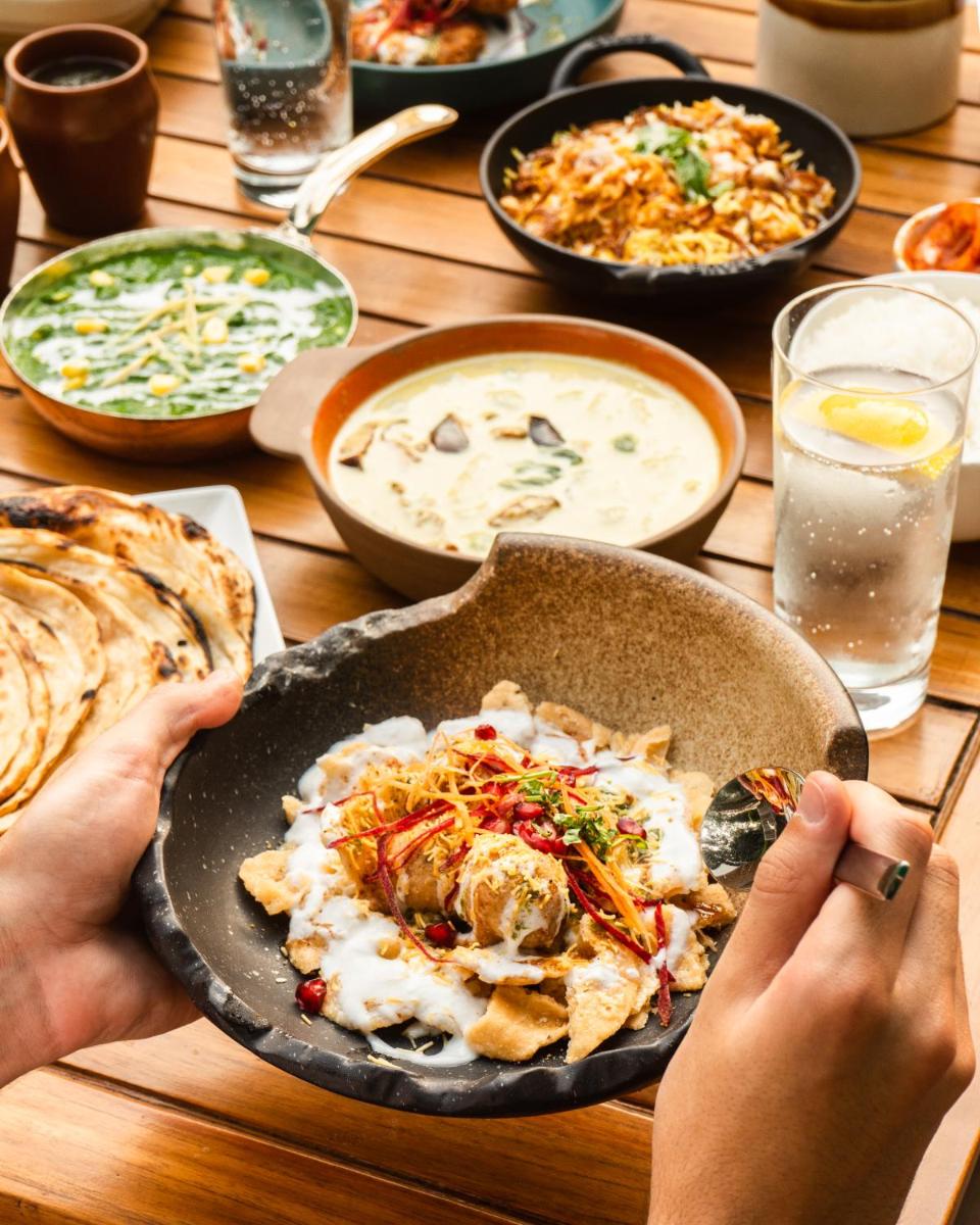 a person holding a pan of food on a table at Shangri-La Eros New Delhi in New Delhi a person holding a pan of food on a table at Shangri-La Eros New Delhi in New Delhi