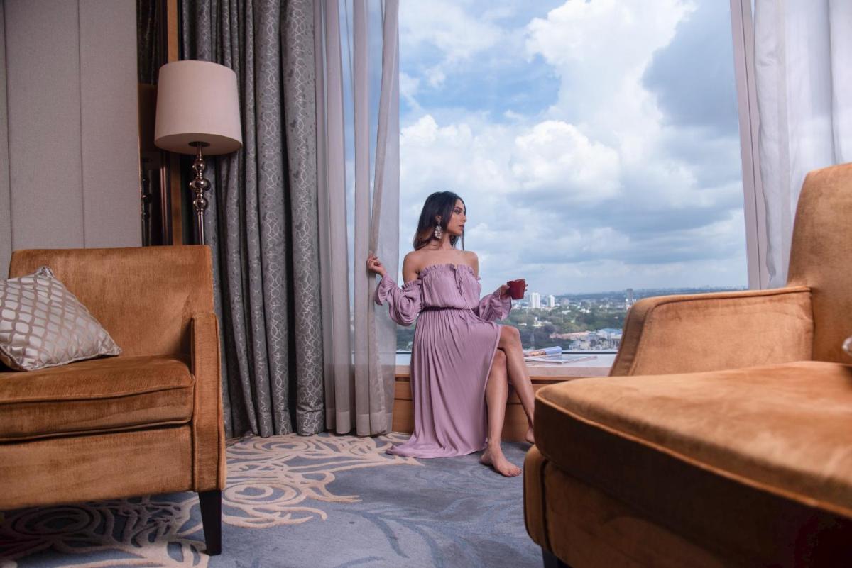 a woman in a pink dress sitting in front of a window at Shangri-La Bengaluru in Bengaluru a woman in a pink dress sitting in front of a window at Shangri-La Bengaluru in Bengaluru