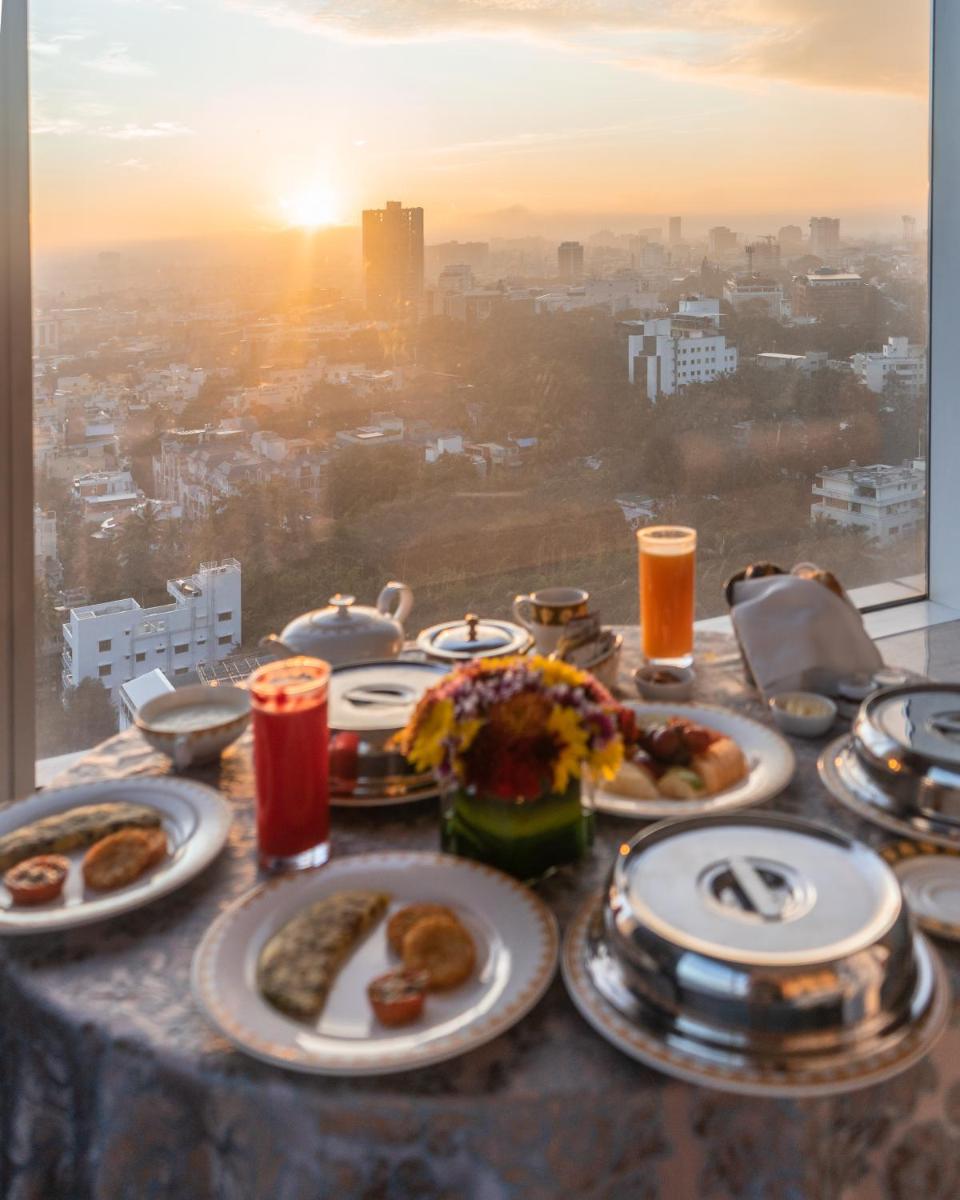 a table with plates of food and a view of a city at Shangri-La Bengaluru in Bengaluru a table with plates of food and a view of a city at Shangri-La Bengaluru in Bengaluru