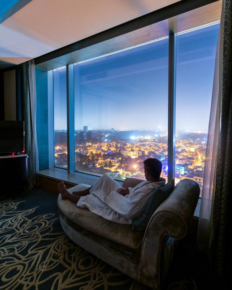 a man laying on a couch in front of a large window at Shangri-La Bengaluru in Bengaluru a man laying on a couch in front of a large window at Shangri-La Bengaluru in Bengaluru