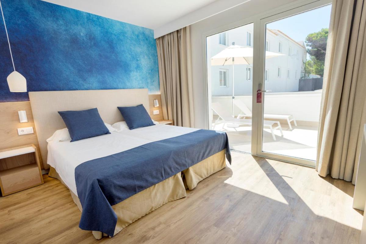Un dormitorio con una cama y una ventana grande. en Parque Nereida Suites Hotel, en Cala Ratjada