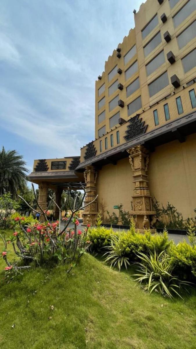a large building with flowers in front of it at Sterlings Mac Hotel in Bengaluru