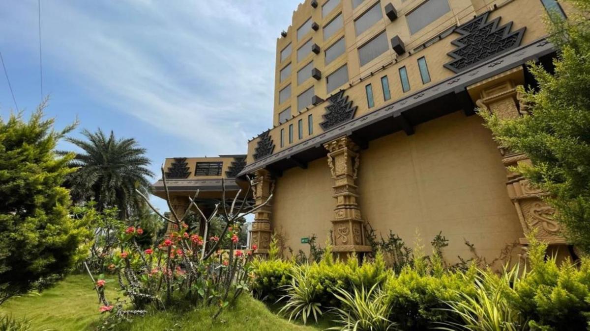 a building with a garden in front of it at Sterlings Mac Hotel in Bengaluru