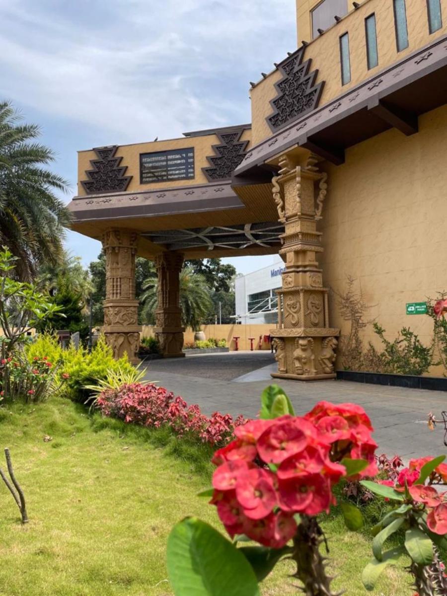 an entrance to a building with red flowers at Sterlings Mac Hotel in Bengaluru