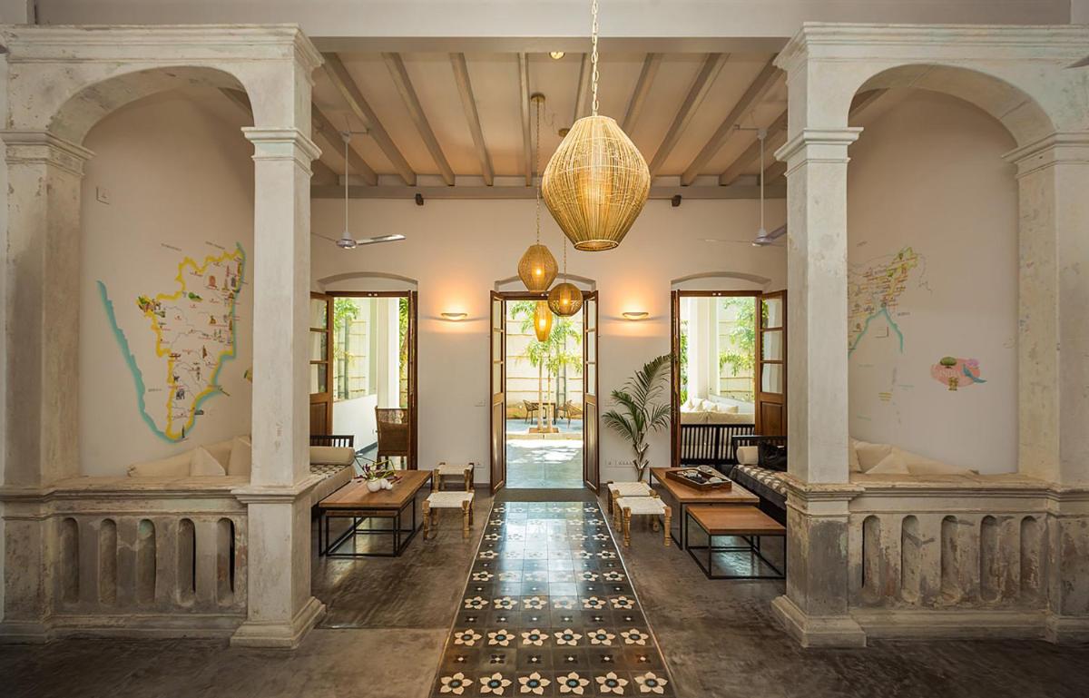 a lobby with tables and chairs in a building at La Villa in Puducherry