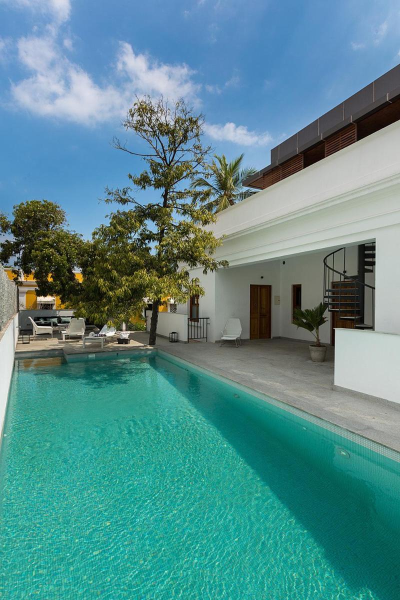 a swimming pool in front of a house at La Villa in Puducherry