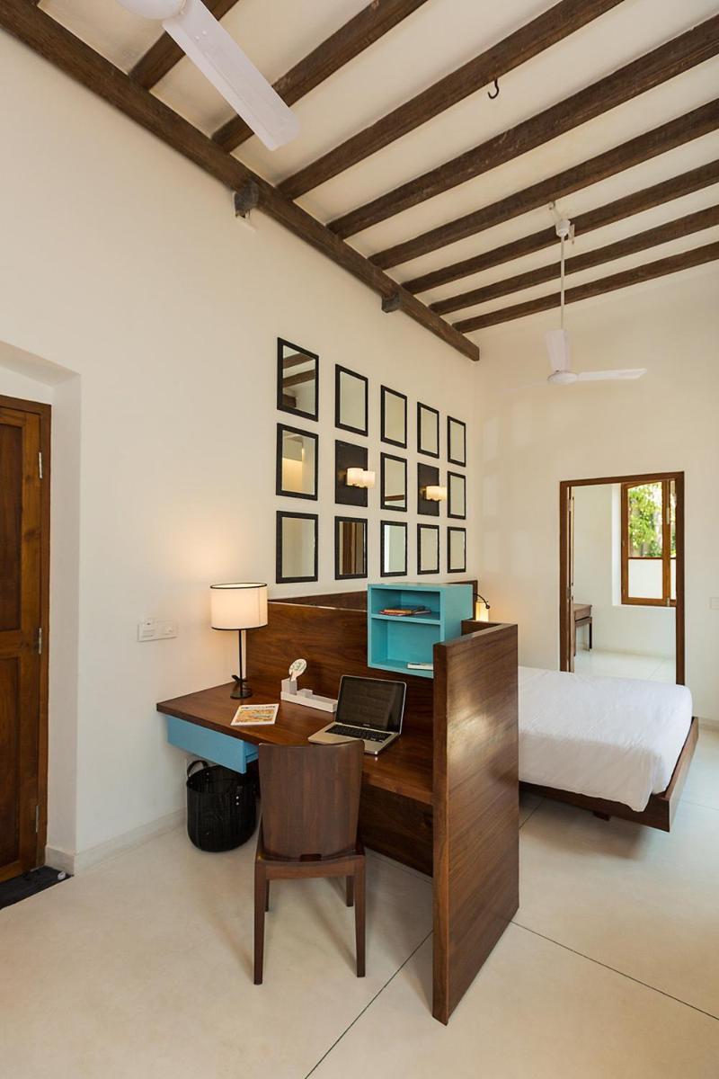 a bedroom with a bed and a desk with a laptop at La Villa in Puducherry