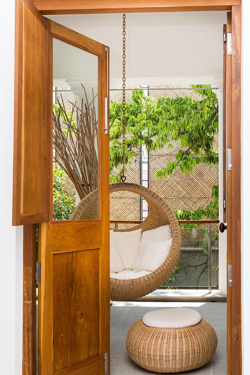 a wicker chair is hanging from a porch at La Villa in Puducherry