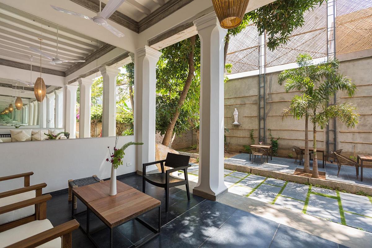 a conservatory with a table and chairs and windows at La Villa in Puducherry
