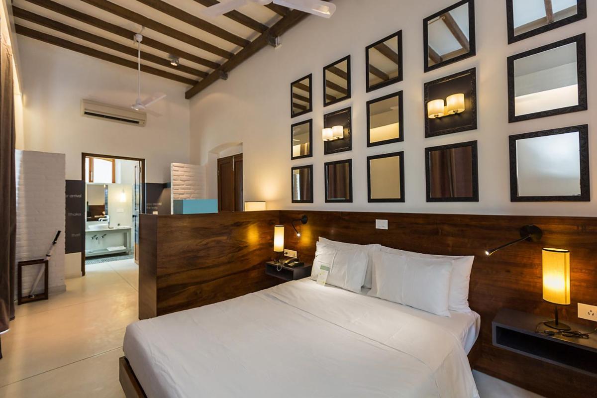 a bedroom with a large bed with a wooden headboard at La Villa in Puducherry