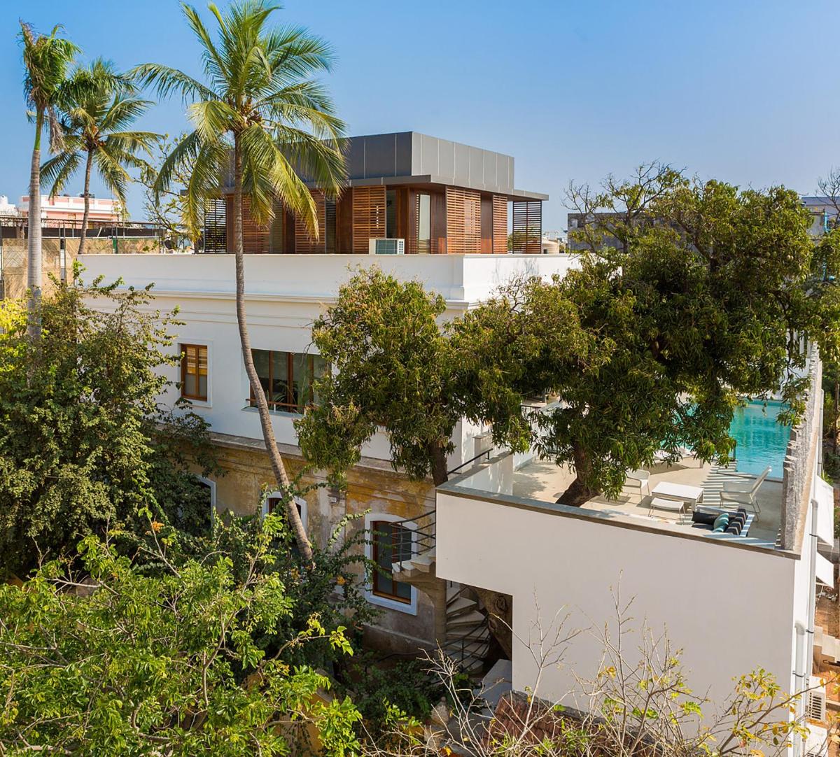 a white building with palm trees in front of it at La Villa in Puducherry