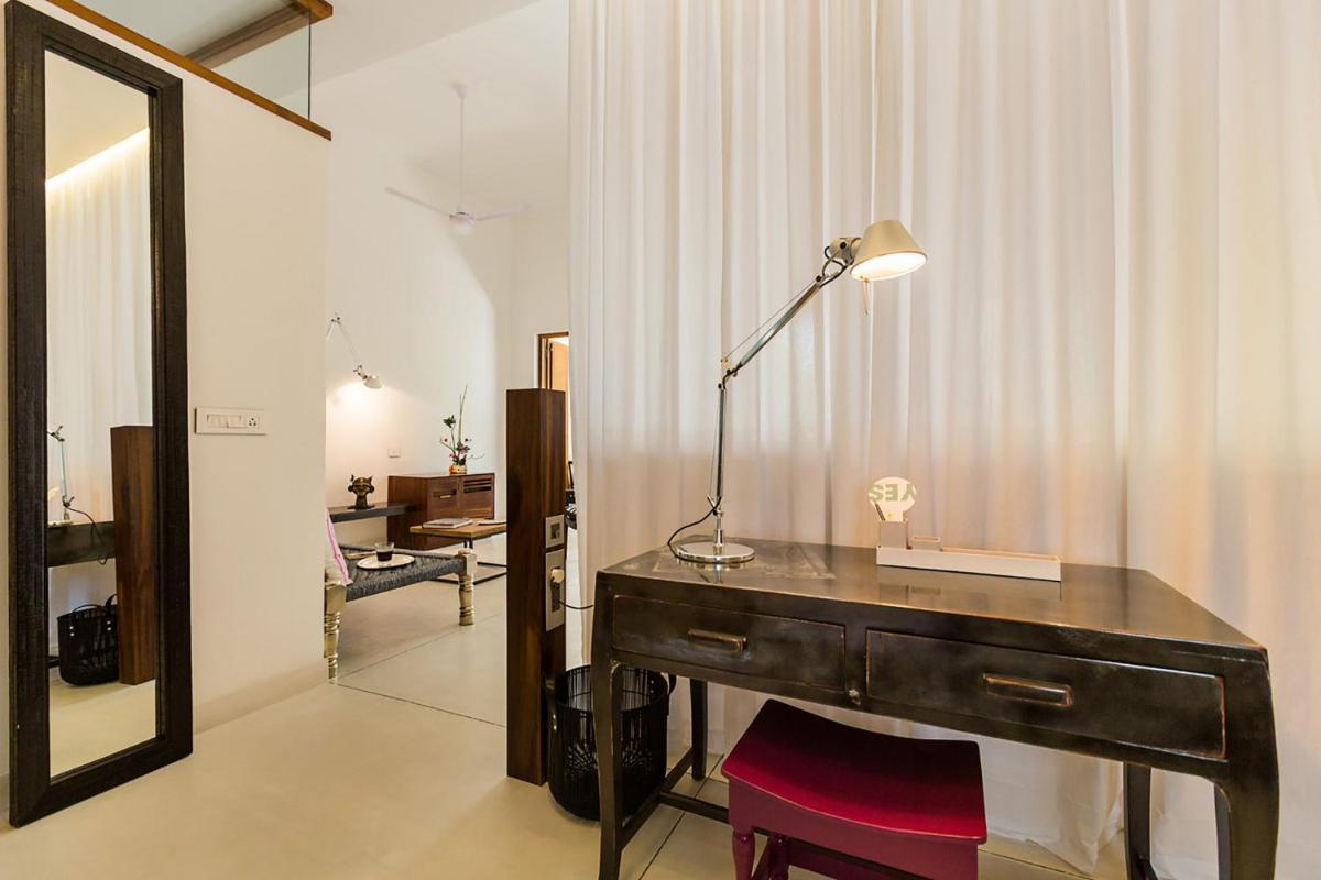 a desk with a lamp and a mirror in a room at La Villa in Puducherry