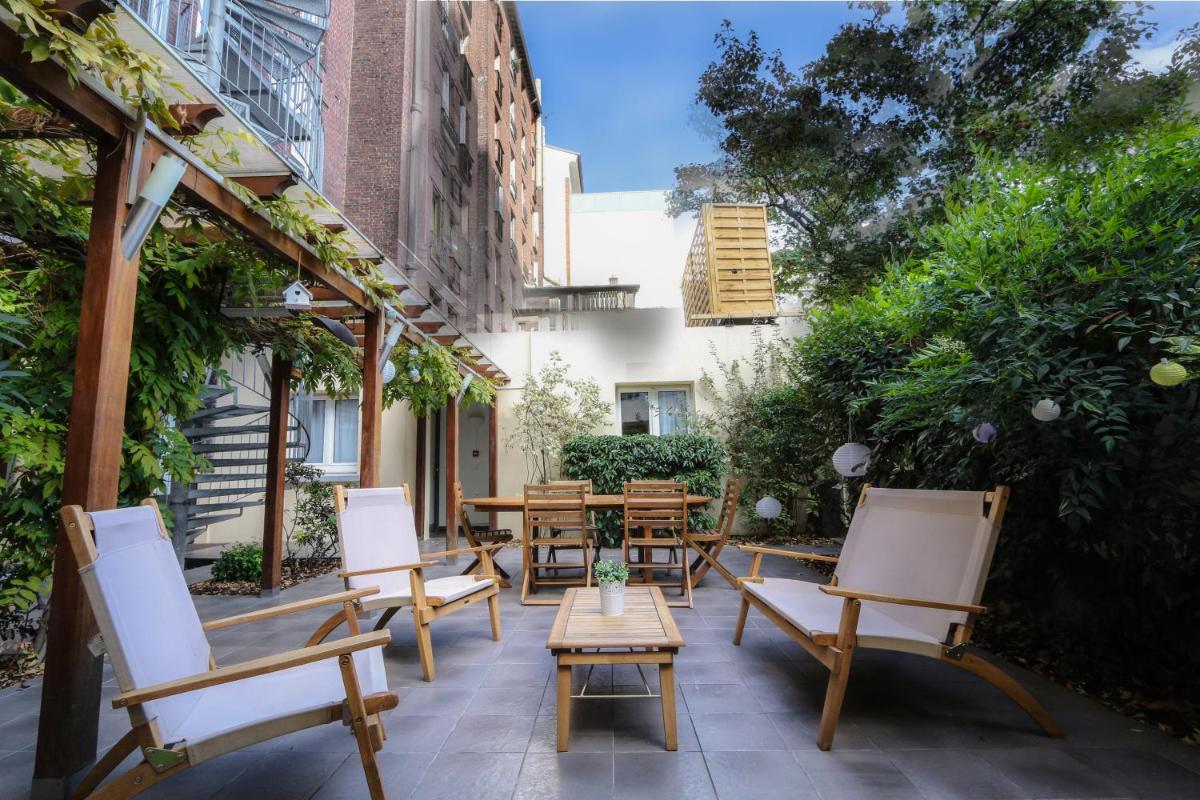 une terrasse extérieure avec des chaises, des tables et des arbres dans l'établissement Atypik Hotel, à Clichy