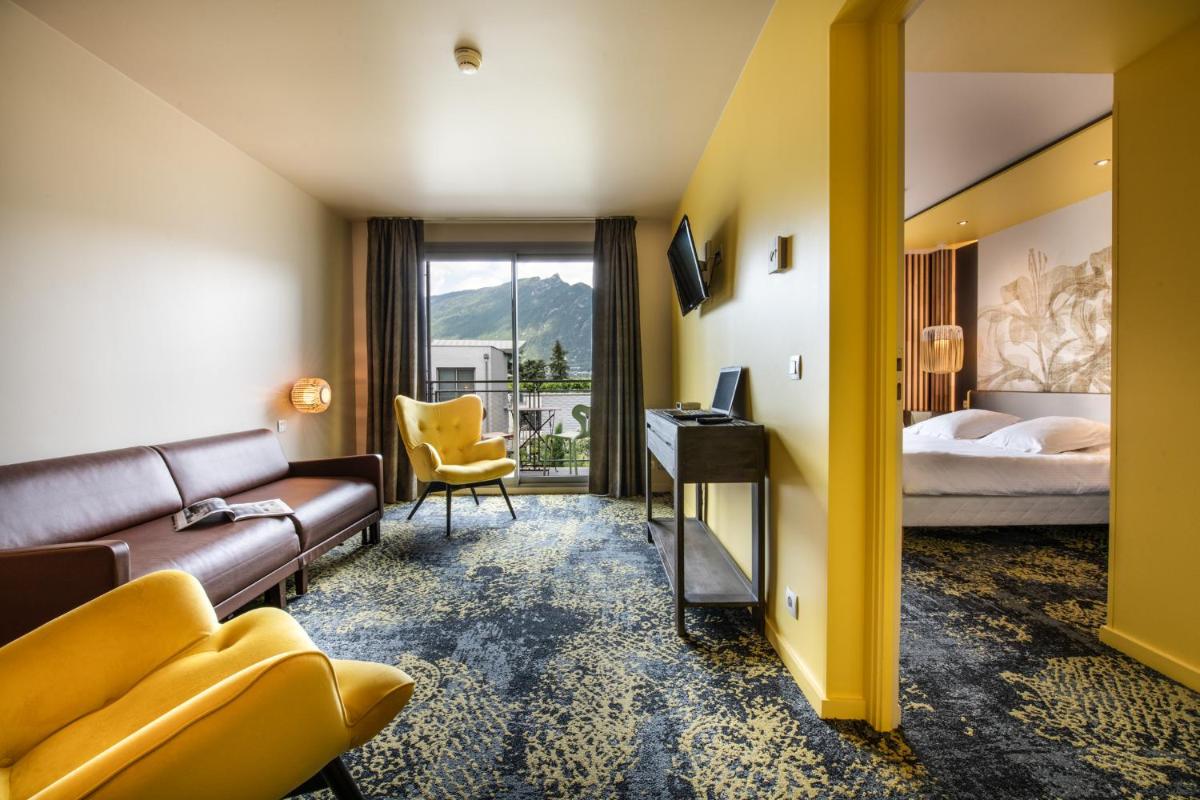 une chambre d'hôtel avec un canapé et un lit dans l'établissement Best Western Aquakub, à Aix-les-Bains