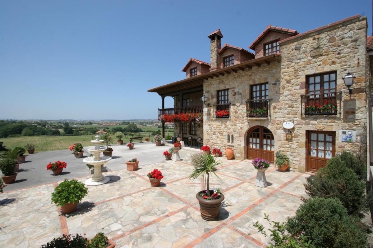 un gran edificio de piedra con un patio con macetas en Hotel "Posada de Cantabria EL SOLAR" -Cenas típicas y Gintonic- Bar -Terraza panorámica, en Galizano