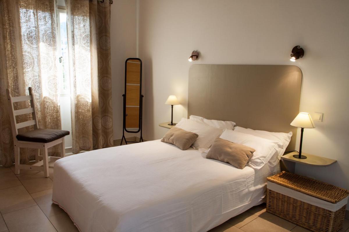 une chambre avec un grand lit blanc et une chaise dans l'établissement Erbalunga - Résidence Les Bosquets - Cap corse Location, à Brando