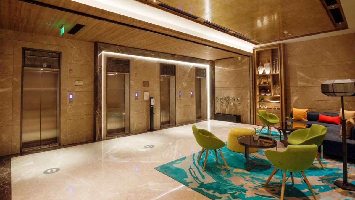 a lobby with green chairs and a table at Holiday Inn Gurugram Sector 90 by IHG in Gurgaon