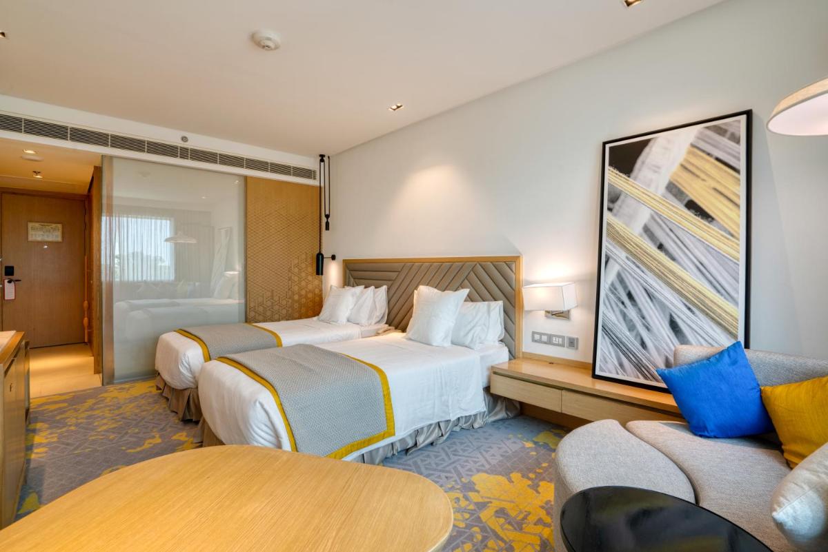 a hotel room with two beds and a couch at Welcomhotel by ITC Hotels, RaceCourse, Coimbatore in Coimbatore