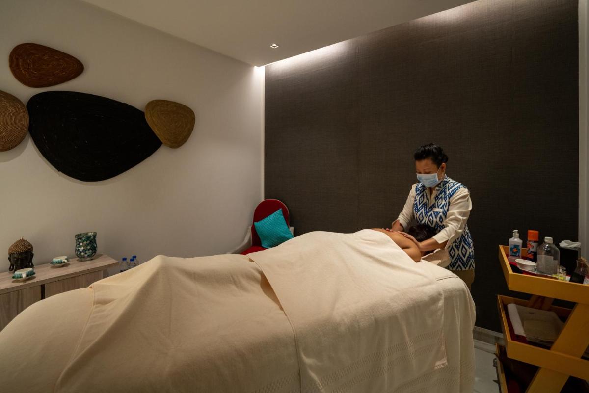 a woman with a face mask sitting next to a bed at Welcomhotel by ITC Hotels, RaceCourse, Coimbatore in Coimbatore