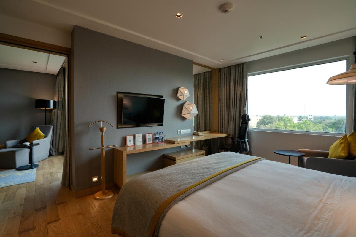 a hotel room with a bed and a large window at Welcomhotel by ITC Hotels, RaceCourse, Coimbatore in Coimbatore