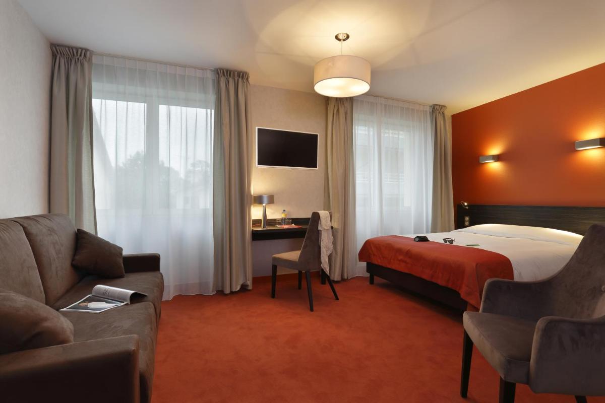 une chambre d'hôtel avec un lit et un canapé dans l'établissement The Originals City, Hôtel Les Thermes de l'Avenue, Dax, à Dax
