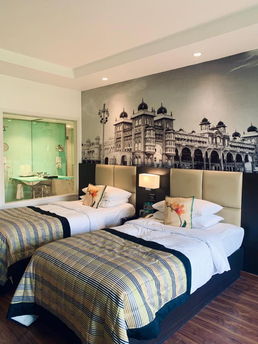 two beds in a hotel room with a mural on the wall at Hotel Royal Orchid Bangalore in Bengaluru