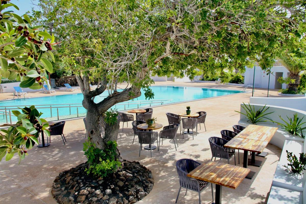 un árbol con mesas y sillas junto a una piscina en Casas Heddy, Well-being Resort, en Puerto del Carmen 70 fotos más
