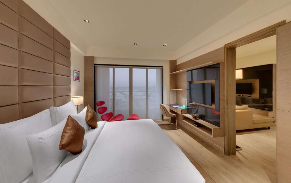 a bedroom with a large bed and a living room at Wyndham Ahmedabad Shela in Ahmedabad