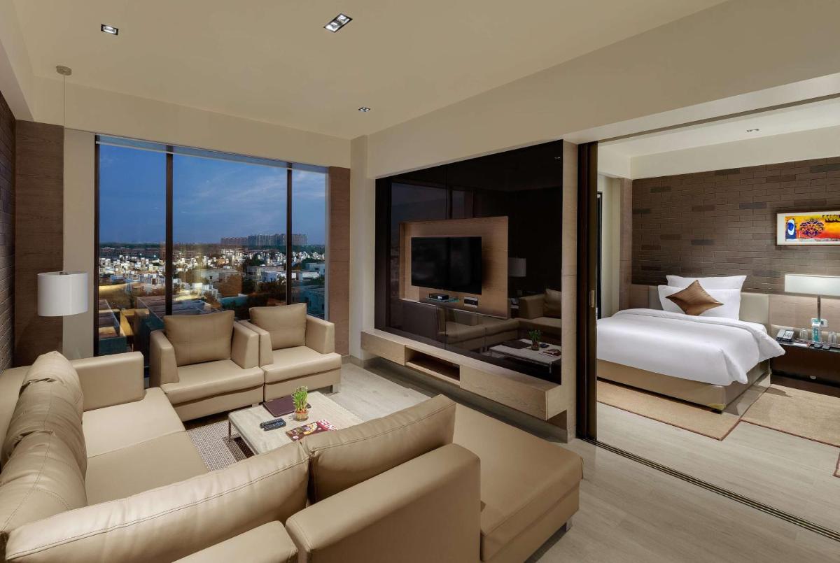 a living room with a bed and a large window at Wyndham Ahmedabad Shela in Ahmedabad
