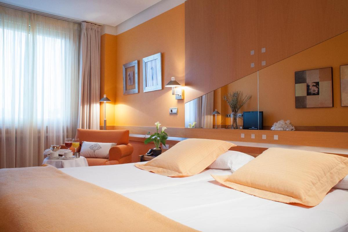 Una habitación de hotel con una cama y una sala de estar. en Hotel Torresport, en Torrelavega