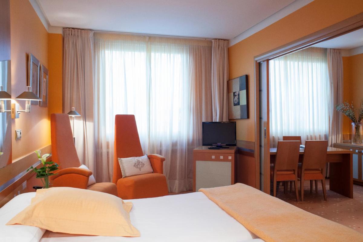 Una habitación de hotel con una cama y un comedor. en Hotel Torresport, en Torrelavega