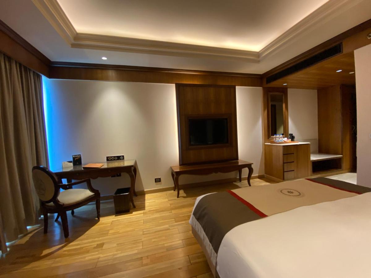 a hotel room with a bed and a desk and a television at Seven Seas Hotel in New Delhi