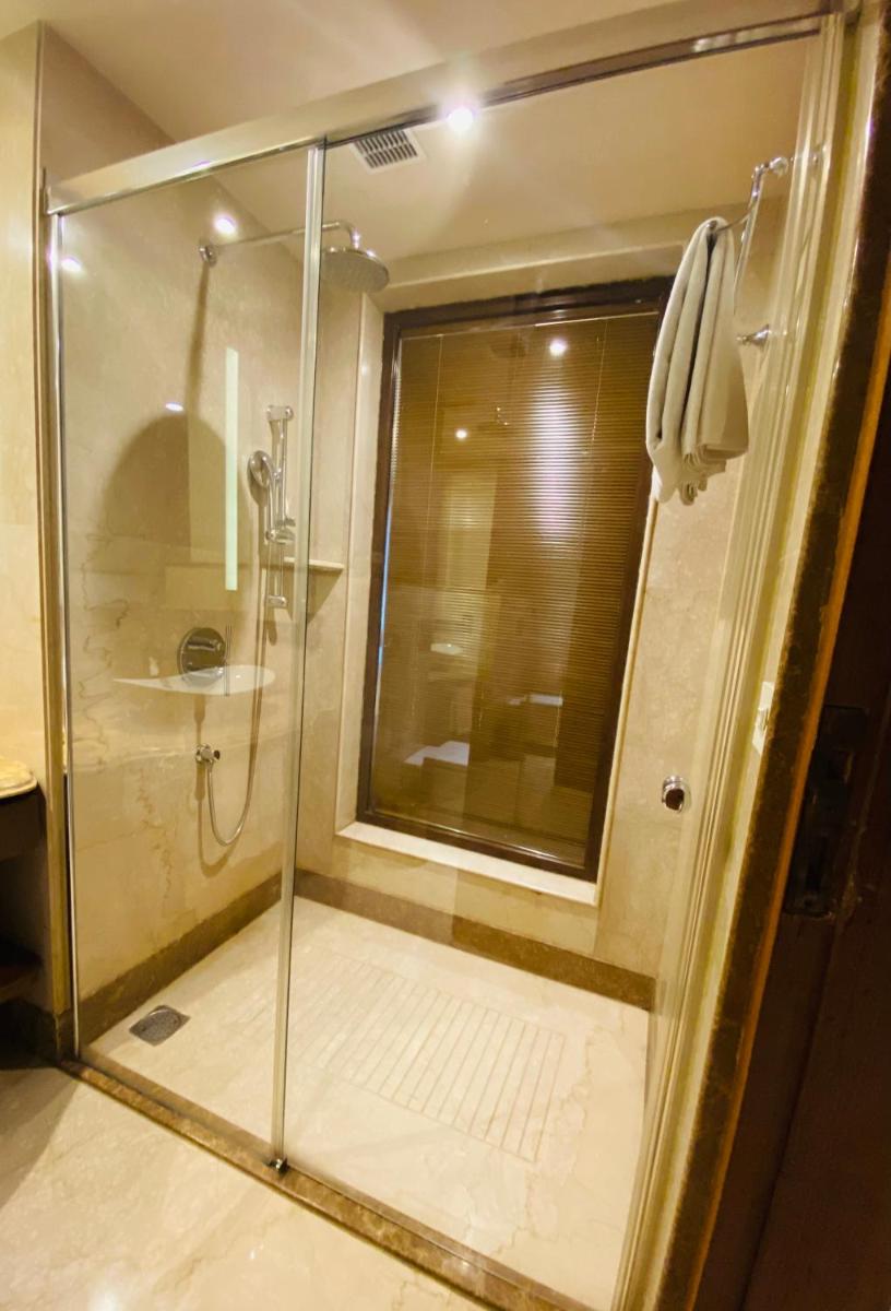 a shower with a glass door in a bathroom at Seven Seas Hotel in New Delhi