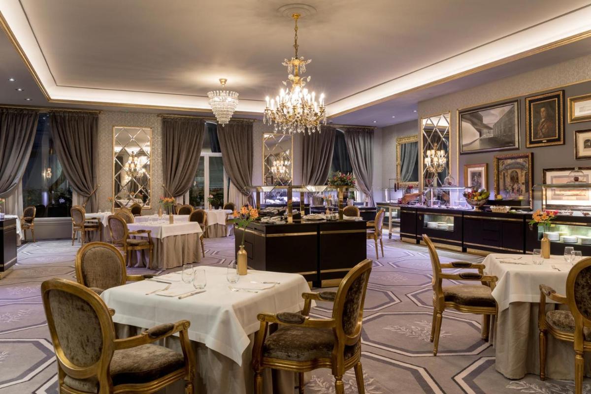 Un restaurante con mesas y sillas y una lámpara de araña. en Wellington Hotel & Spa Madrid, en Madrid