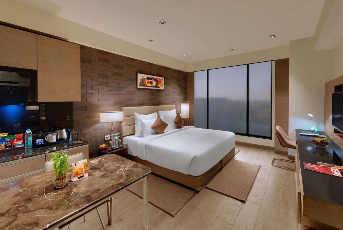 a hotel room with a bed and a television at Wyndham Ahmedabad Shela in Ahmedabad